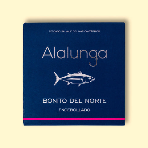Canned white tuna in square blue card packaging with Alalunga in silver, embossed lettering above a diagram of a tuna. There is a purple stripe along the bottom of the packaging.