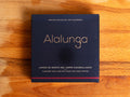 Canned white tuna in square blue card packaging with Alalunga in silver, embossed lettering above a diagram of a tuna. There is a purple stripe along the bottom of the packaging.
