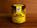 A jar of white tuna fillets in a golden-coloured extra virgin olive oil. There is a green and yellow label on the jar with Bonito del Norte written in black lettering and Conservas Angelachu written in green beneath. The jar is against a wood background.