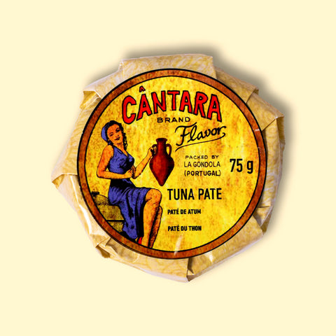 A round tin in a glossy paper wrap with a woman on the front in a blue dress holding a container of olive oil beneath the Cântara logo in red.