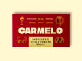 Red box of Carmelo sardines in spicy tomato sauce on a wooden table.