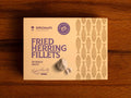 A  tin of herring fillets in cream-coloured packaging with purple lettering by a picture of a garlic bulb and two garlic cloves.