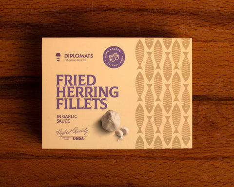 A tin of herring fillets in cream-coloured packaging with purple lettering by a picture of a garlic bulb and two garlic cloves.