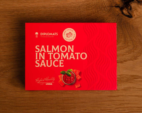 A tin of salmon in red card packaging with pale grey lettering above an image of a diced salmon fillet round a bowl of tomato sauce topped with a sprig of basil.