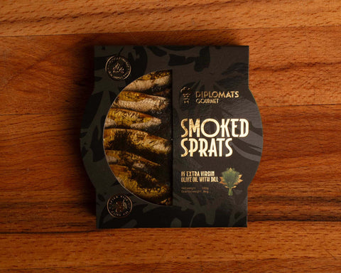 Smoked sprats in extra virgin olive oil, presented in a semi-open black packaging, showing sprats lightly covered in green dill.