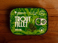 Trout fillet with dill in extra virgin olive oil, packaged in green with black borders, featuring an image of fresh dill.