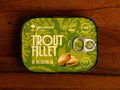 Trout fillet in pistachio oil in green packaging with black borders, featuring an image of pistachio nuts.