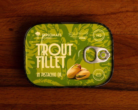 Trout fillet in pistachio oil in green packaging with black borders, featuring an image of pistachio nuts.