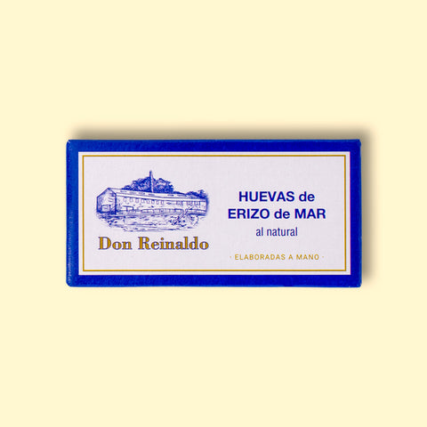 A rectangular box depicting a drawing of the cannery, the brand name Don Reinaldo and text in Spanish. It is a small tin with sea urchin roe and you can read 'hand packed'