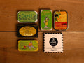 A selection of colourfully-packaged tinned sardines, mackerel and tuna against a wood background.