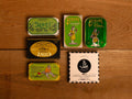A selection of colourfully-packaged tinned sardines, mackerel and tuna against a wood background.