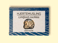 Limfjord cockles in white and blue packaging, featuring an illustration of a cockle, with text beneath reading lightly salted.