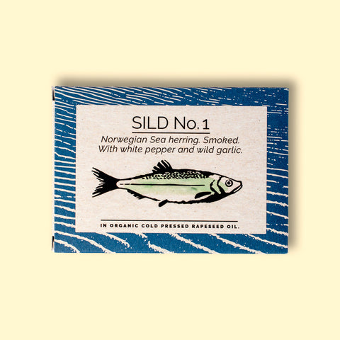 A rectangular box with a blue border and a painting of a herring on the front, against a wood background