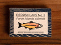 A tin of Faroe Islands salmon in white packaging with blue borders, featuring an illustration of a salmon with the description of sea buckthorn and lemon verbena below.