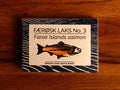 Tinned Faroe Islands Salmon with white and blue packaging, featuring an illustration of a salmon with text beneath reading smoked over beech wood.