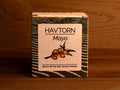 A tin of mayonnaise with buckthorn in light grey square card packaging with blue borders, featuring an illustration of a buckthorn.