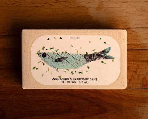 Sardines in ravigote sauce in rectangular white and cream packaging, featuring a central illustration of a blue and black coloured sardine.