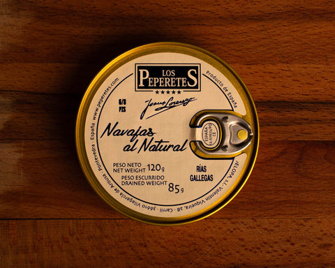 A round, golden-coloured tin with a cream sticker applied to it with dark blue lettering, against a wood background.