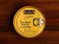 Bright yellow tinned of sardines. The Spanish writing says Sardines in Galician sauce. They are perfectly placed on a wooden table top