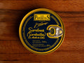 A dark blue tin with golden borders containing small sardines, featuring the Los Peperetes label at the top, set against a wooden backdrop.
