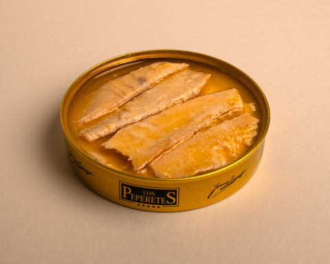 An open circular golden tin containing fillets of ventresca in jersey butter.