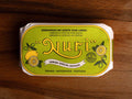 A tin of sardines with lemon in lime green packaging, featuring a lemon graphic and the word 'Nuri' written in bold yellow lettering at the centre, with 'Lemon Special Edition' written below.