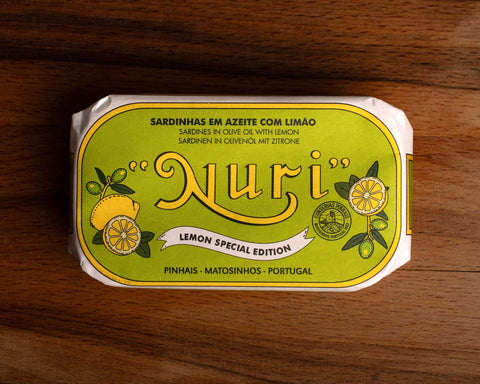 A tin of sardines with lemon in lime green packaging, featuring a lemon graphic and the word 'Nuri' written in bold yellow lettering at the centre, with 'Lemon Special Edition' written below.