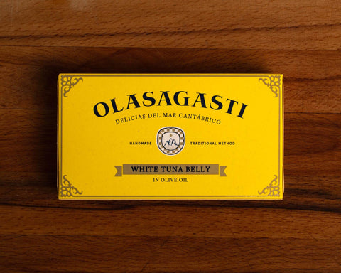 A tin of white tuna in olive oil, packaged in a yellow rectangular box featuring the brand name Olasagasti.