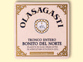 A square tin of tuna with an ornate gold border and Olasagasti written in black lettering against a pale pink background