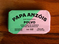 A rectangular tin of octopus in extra virgin olive oil with green and pale lilac paper packaging against a wood background.