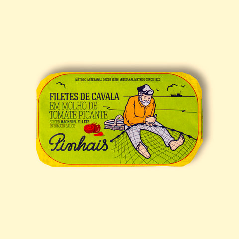Mackerel fillets in spicy tomato in a green paper wrap with a yellow border. There is a drawing of a fisherman mending a fishing net on the front., and an image of a tomato and a red chilli pepper