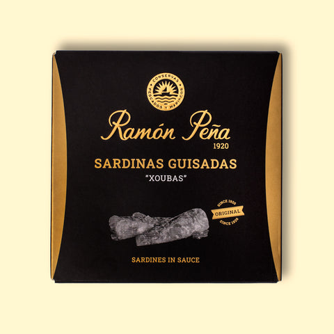 A tin of small sardines in black and gold packaging. Ramón Peña is written in gold lettering above a silver grey image of a sardine