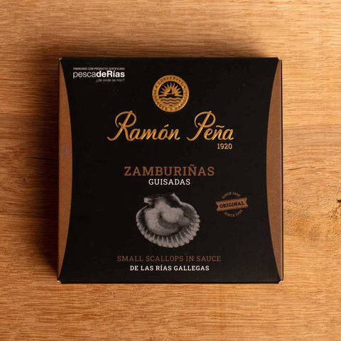 A tin of scallops in black and gold packaging. Ramón Peña is written in gold lettering above a silver grey image of a scallop shell.