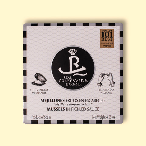 Tinned mussels in black and white card packaging with a small illustration of an open mussel on the front. The tin is against a wood background.