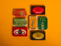 A selection of colourfully-packaged tinned scallops, tuna, mackerel and sardines against a yellow background.