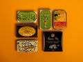 A selection of colourfully packaged tins of sardines and tuna against a yellow background.