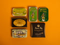 A selection of colourfully packaged tins of sardines and tuna against a yellow background.