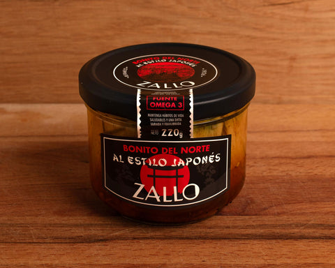 A jar of tuna fillets with a black and red label featuring Japanese iconography against a wood background.