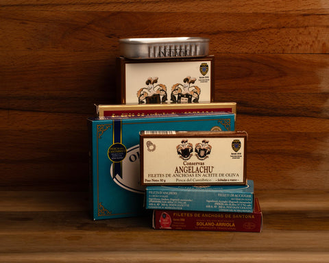 Three large tins of Cantabrian anchovies with four smaller tins of anchovies in different colours and designs.