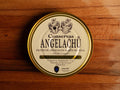 A tin of 32 cantabrian anchovy fillets in a circular white container with golden borders, set against a wooden backdrop.