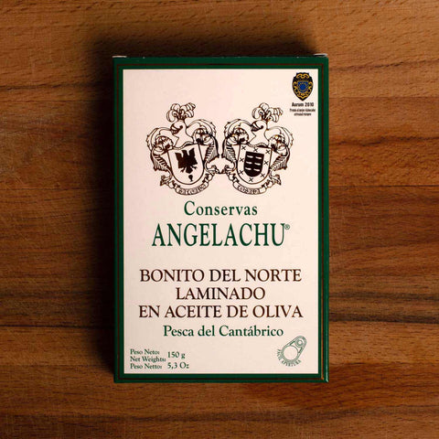 A tin of Bonito del Norte tuna in rectangular white packaging with a green border and lettering against a wood background