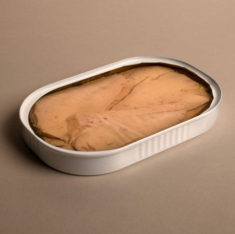 Thinly sliced tuna in a slim white tin on a pale background.