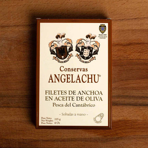 A tin of large Cantabrian anchovies in rectangular cream packaging with a brown border, against a wood backdrop.
