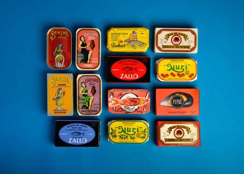 A selection of colourfully packaged tinned fish on a light blue background