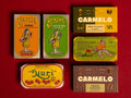 Six vintage Spanish tinned fish boxes arranged on a solid red background. The boxes feature retro designs with illustrations .