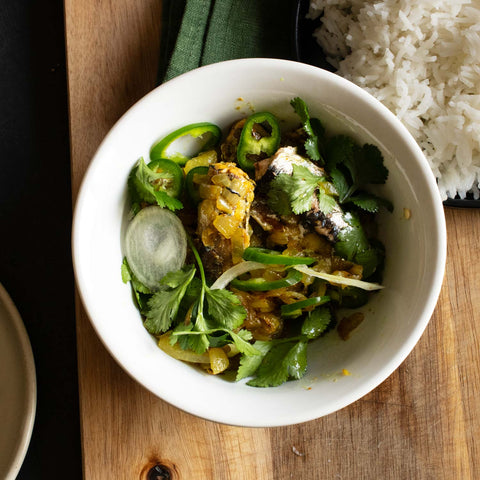 An open tin of sardines, with peeled and sliced garlic clove. Finished with chopped coriander, chopped green chilli and served with hot basmati rice.