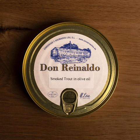A round gold-coloured tin with a sticker on the front. Don Reinaldo is written on the sticker in gold lettering below a drawing of the cannery.