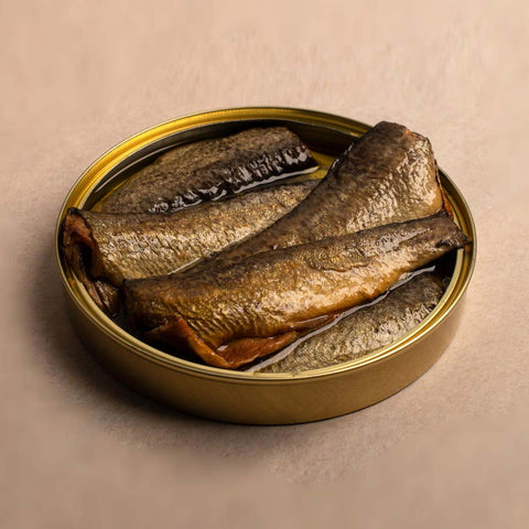 A gold-coloured open tin with five trout in olive oil inside, against a pale background