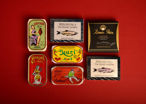 A selection of colourfully packaged tinned fish on a red background