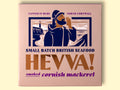 Box containing Cornish mackerel from Hevva! The box is illustrated with a fisherman calling out over the Cornish coast with cliffs and a lighthouse in the background. The box is colourful with the Hevva name written in golden, embossed lettering